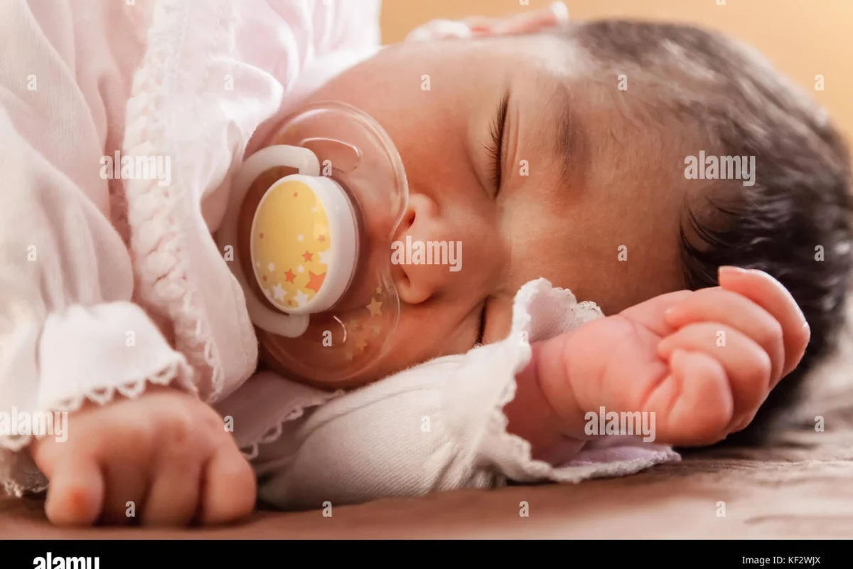 Newborn baby sleeping in a safe crib setup with diapers and feeding essentials nearby